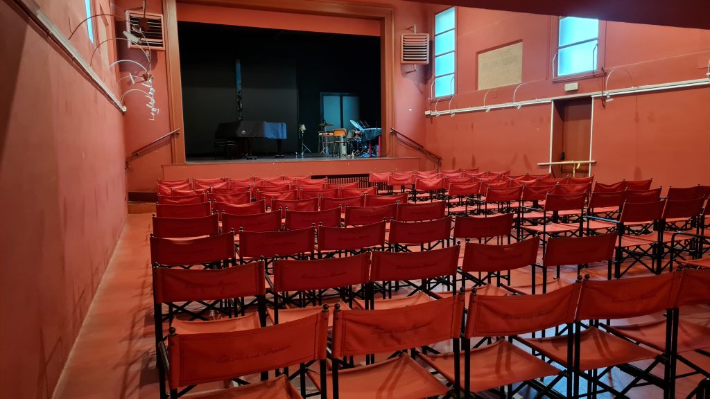 Sala teatrale con sedie rivolte verso il palco.