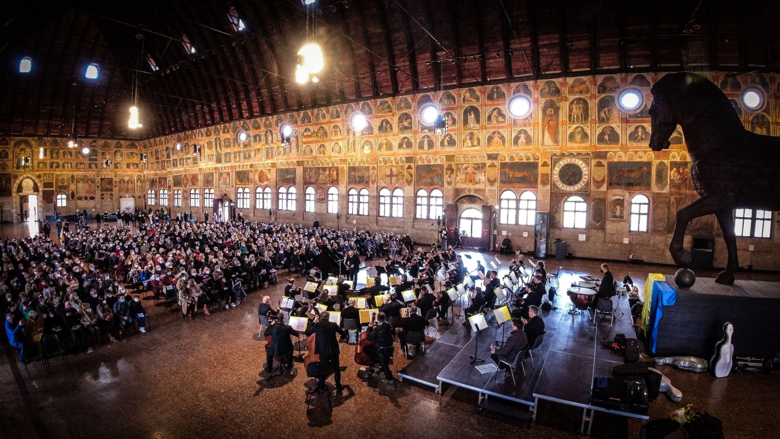 Un gruppo di musicisti si esibisce dal vivo davanti a un pubblico, all'interno del Palazzo della Ragione.
